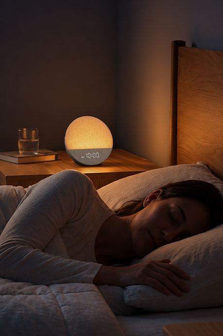 Woman sleeping beside a Dreamegg Sunrise 1 with warm bedside light