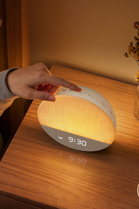 Hand using the top controls on a glowing Dreamegg Sunrise 1 alarm clock