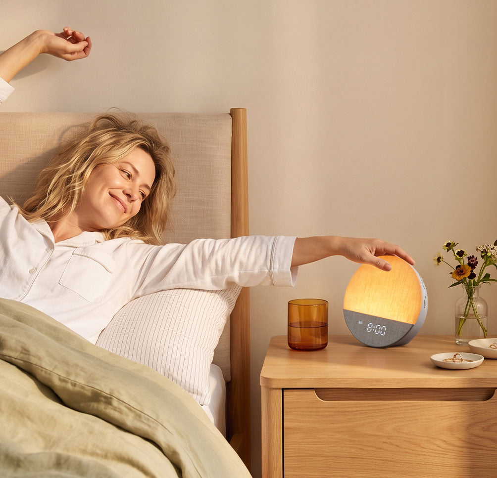 Woman waking and reaching toward a Dreamegg Sunrise 1 on her bedside table